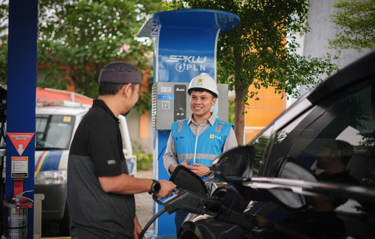 Ilustrasi pengguna kendaraan listrik sedang mengisi daya di SPKLU.